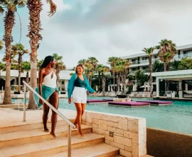 Mujeres caminando junto a piscina en resort tropical de lujo.