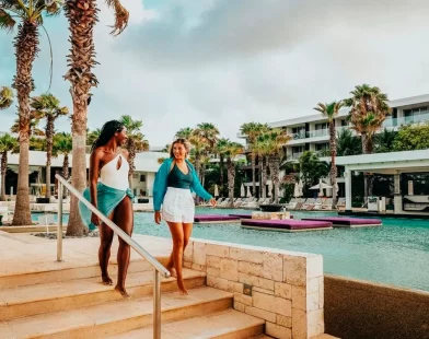 Mujeres caminando junto a piscina en resort tropical de lujo.